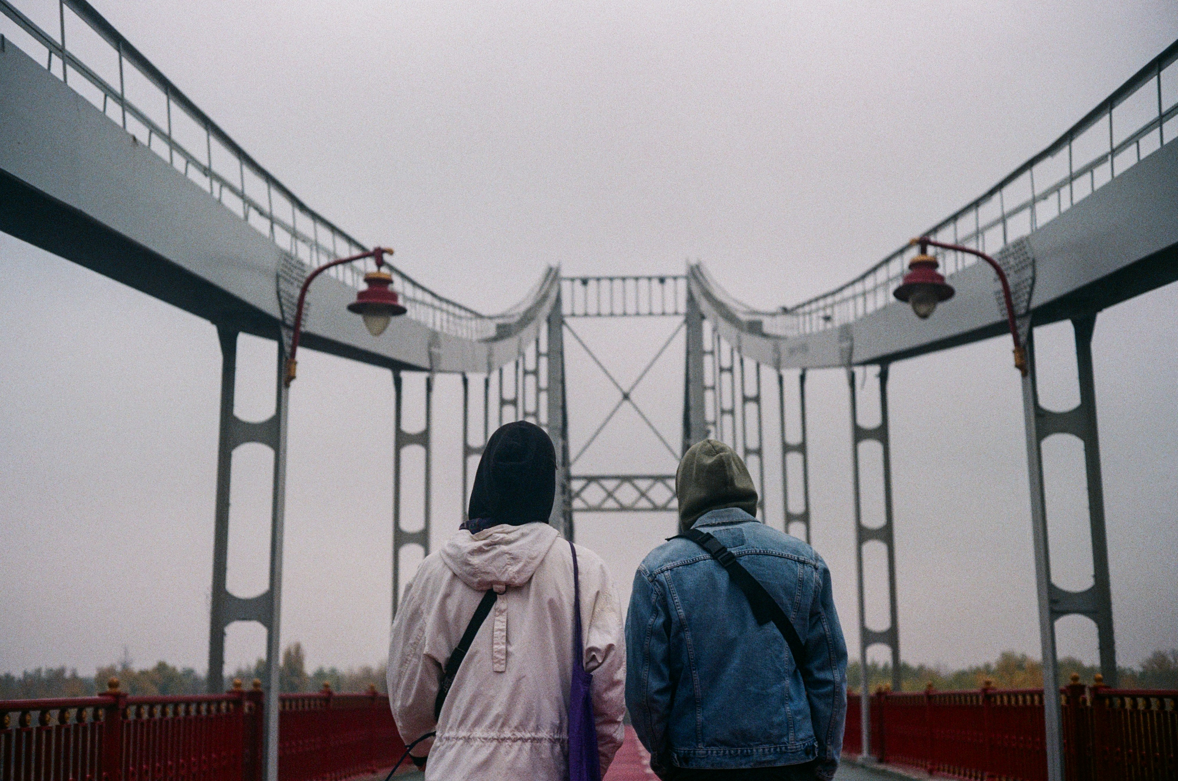 man in blue jacket standing on bridge during daytime